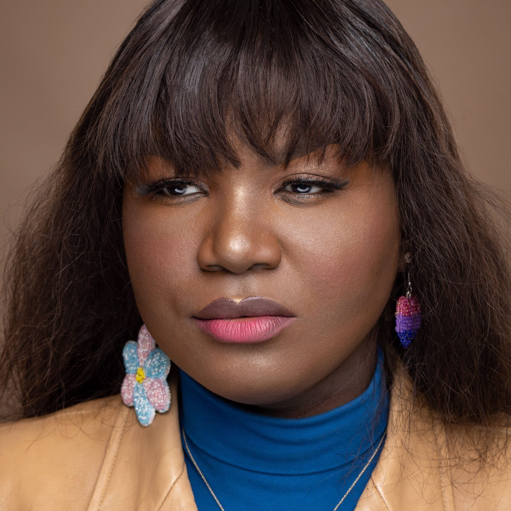Portrait of Jacq Brasseur, a non-binary white person with long blonde hair and dark rimmed glasses. They are looking out of frame, to the left, with a small smile on their lips.